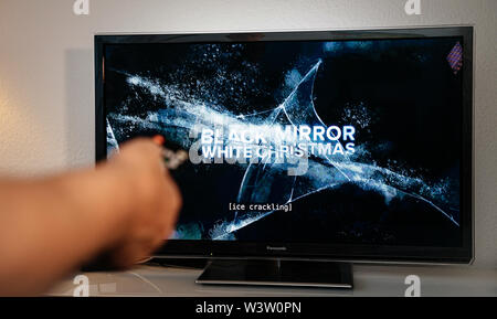 Paris, Frankreich, 10.Juli 2019: älterer Mann hand drehen mit Fernbedienung beobachten die Black Mirror auf Netflix - es ist eine britische Science-Fiction-Anthologie TV-Serie erstellt von Charlie Brooker, Stockfoto