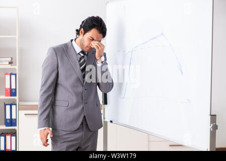 Theyoung gut aussehender Geschäftsmann vor Whiteboard Stockfoto