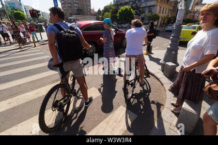 Bukarest, Rumänien - Juli 01, 2019: Menschen auf elektrische Motorroller und Fahrräder warten auf die Straße an der Sieg Avenue Fahrradweg in der Bu zu überqueren Stockfoto