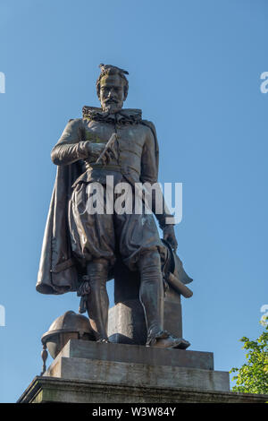 Brügge, Flandern, Belgien - 17 Juni, 2019: Nahaufnahme von Simon Stevin Statue unter blauem Himmel. Einige grüne Laub. Taube auf den Kopf. Stockfoto