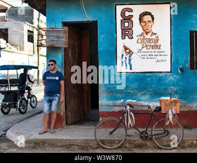 Ein Mann steht an der Ecke in Trinidad, Kuba neben einem Fahrrad mit frisch gefangenen Fisch. Stockfoto