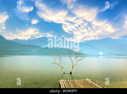 Einsamer baum Zweige in der großen Lagune in der Dämmerung mit dramatischen Himmel begrüßen den neuen Tag Stockfoto