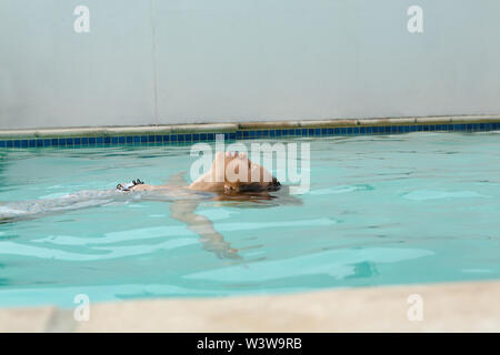 Frau mit geschlossenen Augen schwimmen im Pool im Hinterhof Stockfoto