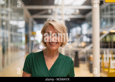 Happy Geschäftsfrau, die in der Flur am Büro Stockfoto