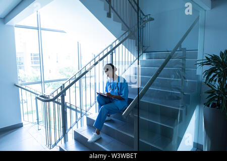 Weibliche Chirurg sitzt auf der Treppe des Krankenhauses Stockfoto
