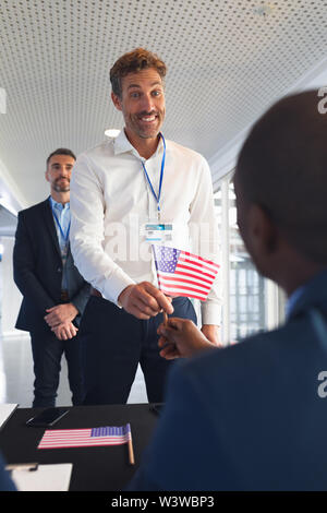 Unternehmer, die im Besitz einer amerikanischen Flagge bei Anmeldung zur Konferenz Tabelle Stockfoto