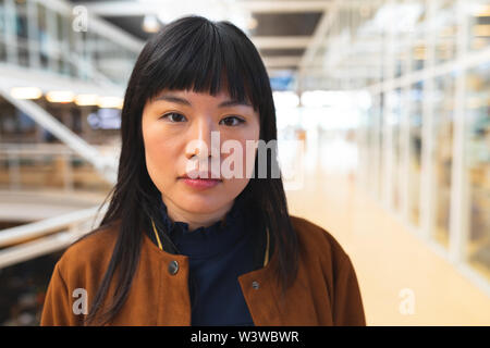 Geschäftsfrau, die an der Kamera, die in der Flur am Büro Stockfoto