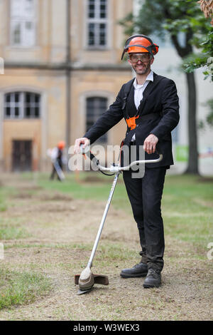 16 Juli 2019, Sachsen, Wermsdorf: Aktion Künstler Ralf Witthaus Stände mit einer motorsense in der ehemaligen barocken Garten im Park von Schloss Hubertusburg. Europas größte Hunting Lodge hat einen Bruchteil seiner verlorenen Garten zurück. Mit rund 40 Freiwilligen, die Kölner Aktionskünstler ist seit dem 1. Juli frei, einige der zentralen Formen der Schmuck in der ehemaligen Park schneiden. Auf 10.000 Quadratmetern, die zentrale Achse und zentrale Teile des barocken Garten Zusammensetzung haben auferstanden - ein Zehntel der ehemaligen Komplex. Aber die Besucher der 'Sächsische Versailles' haben sich zu beeilen, weil es eine temporäre ist Arbeit. Stockfoto