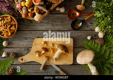 Pilze auf alten hölzernen Hintergrund. Karte auf Herbst oder Sommer. Wald Ernte. Steinpilze, Pfifferlinge, Blätter, Beeren. Ansicht von oben. Flach Stockfoto