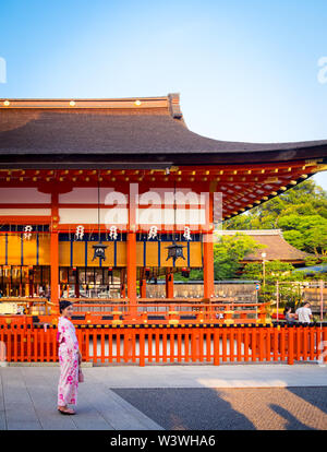 Ein japanisches Mädchen kleidet sich im Sommer vor dem Romon-Tor (Haupttor) des Fushimi Inari-Taisha-Schreins in der Nähe von Kyoto, Japan. Stockfoto