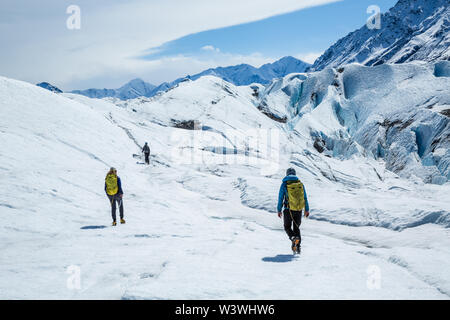 Drei Klettern und Trekking Guides wandern über weiße Gletscher Eis. Sie gehen mit Steigeisen der Matanuska Gletscher in Alaska. Stockfoto