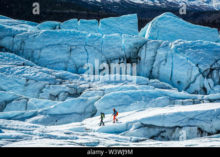 Ein Mann und eine Frau laufen Sie entlang der weißen Eis auf der Matanuska Gletscher in Alaska. Diese beiden Glacier Guides sind Scouting eine Route durch das Zerschrundeten ice t Stockfoto