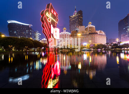 Macao, CHINA - 23. April 2017: Die Lichter von einem berühmten Casino-Betreiber Wynn reflektieren auf dem Wasser mit dem Lisboa Casino-Turm im Hintergrund. Macau rece Stockfoto