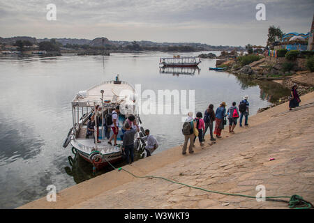 Gruppe von Touristen aussteigen ein Boot ein Nubisches Dorf zu besuchen Stockfoto