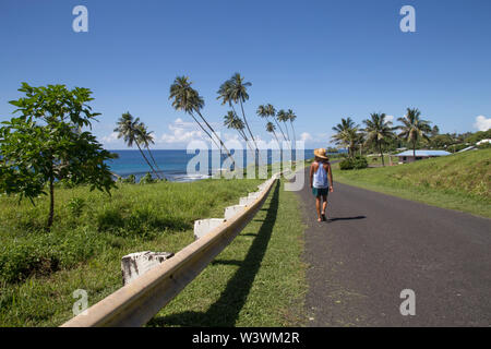 Ein Mann, in kurzen Hosen und Leibchen zu Fuß auf die Küste Straße, Samoa Stockfoto