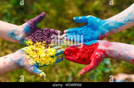 Hände Handflächen junger Menschen in lila, gelb, rot, blau Holi Festival Farben bedeckt isoliert. Stockfoto
