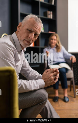 Ernsthaft traurig, grauhaariger Mann mit seinem Daumen drücken Stockfoto