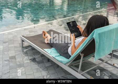 Frau mit Tablet und Entspannen im Schwimmbad im Sommer Stockfoto