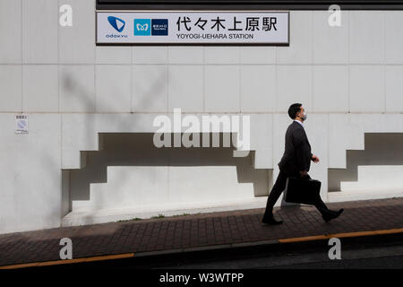 Ein junger japanischer Salaryman geht an der Yoyogi Uehara Station in Tokio, Japan, vorbei. Stockfoto