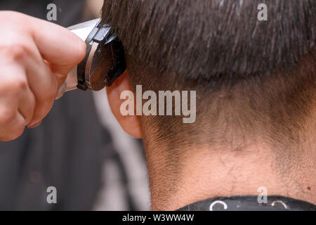 Frau Friseur schneidet die Haare des Mannes mit elektrischer Haarschneider Trimmer Stockfoto