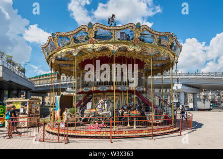 Kiew, Ukraine - Juli 13, 2019: Alte vintage Karussell Attraktion bei Post Platz in Kiew, Ukraine. Schiffe am Ufer des Dnjepr River. Stockfoto