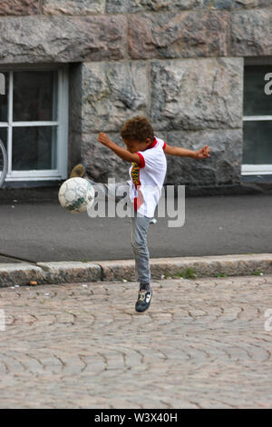 Junge kicks Itäinen Papinkatu Ball während Kalllio Block Party 2016 in Helsinki, Finnland Stockfoto