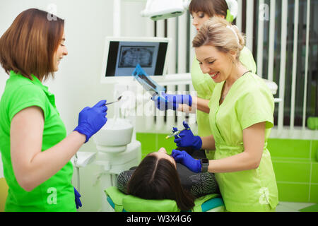 Zahnärzte in der Zahnarztpraxis im Gespräch mit der Patientin und die Vorbereitung der Behandlung Stockfoto