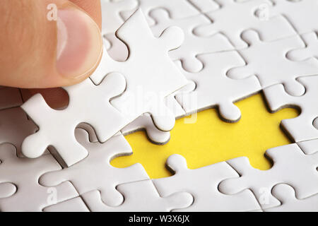Hand das letzte Stück des Puzzles zur Vollendung der Aufgabe Stockfoto