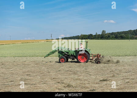 Landwirt Traktor schaltet das Gras für eine bessere Trocknung Stockfoto