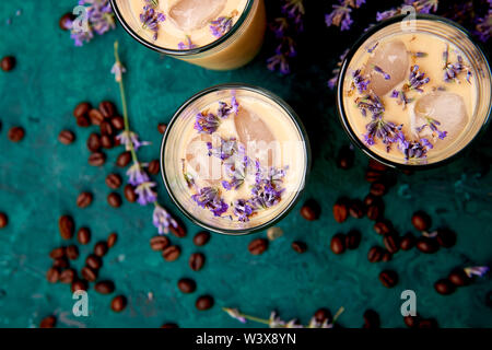 Sommer trinken Eiskaffee mit Lavendel in Glas und Kaffeebohnen auf grünem Hintergrund. Guten Morgen Konzept. Baeutiful Eis Kaffee. Stockfoto