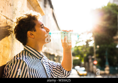 Sommer in der Stadt, Jungen Mann trinken eine Flasche Wasser Stockfoto