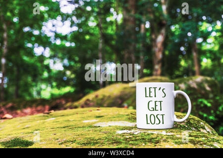 Inspirierende Reise zitiere - Let's Get Lost auf die weiße Tasse. In der Nähe von weißen Becher für ihre Mock-up im tropischen Regenwald. Stockfoto