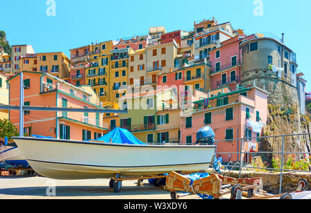 Schöne Aussicht von Manarola Stadt mit Fischerboot im Vordergrund und kleinen bunten Häusern am Hang, Cinque Terre, La Spezia, Italien Stockfoto