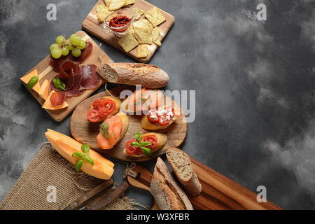 Brushetta oder traditionelle spanische Tapas. Vorspeisen mit italienischen Antipasti, Snacks. Vielzahl von kleinen Sandwiches mit Kirschtomaten, Lachs, Stockfoto