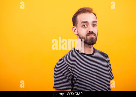 Portrait Junge attraktive bärtiger Mann mit einem gestreiften T-Shirt auf gelben Hintergrund. Kaukasische Mann. Stockfoto