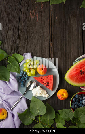 Gesundes Frühstück. Frische saftige Früchte und Hüttenkäse in Platten auf einem Holztisch mit Platz für Text kopieren. Stockfoto