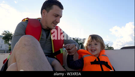 Vater und Sohn auf dem Boot in Schwimmwesten Stockfoto