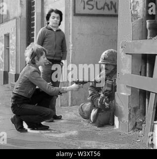 Eingereicht - 01. Januar 1980, Berlin: Berlin/Bezirke/Kreuzberg/20.3.1980 Skalitzer Straße. Amerikanische Soldaten werden in Straßenschlachten in der Kreuzberger Sanierungsgebiet engagiert. Der ganze Block ist leer, graeumt von Mietern, die von Spekulanten. Alles ist abgerissen und durch Neubauten ersetzt. Die Amerikaner verwenden die Ruinen für Krieg Spiele während des Kalten Krieges. Foto: Ein deutscher Junge mit einer Spielzeugpistole//USA/Militär/Verbündeten / Beruf macht und Kalter Krieg/Umbau/Bau/*** Local Caption *** Allyed/Amerikaner/Kalten Krieges amerikanische Soldaten warten auf Kommunisten in Kreuzberg. Stockfoto