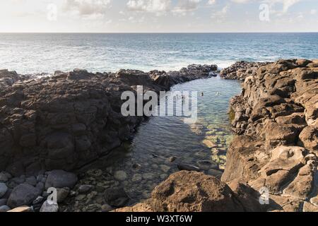 Queen's Bad ist ein tide pool unter den vulkanischen Felsen am Strand in Princeville Kauai, Hawaii, USA, beliebt bei Touristen, aber gefährlich bei rauer See Stockfoto