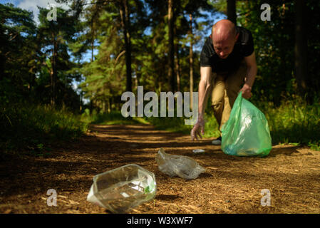 Man Müll sammeln in den Wald. Beim Joggen oder Laufen. Plogging Konzept Stockfoto
