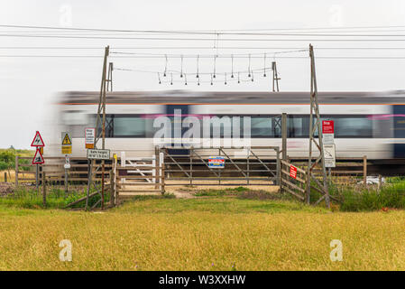 Unbeaufsichtigte Bahnübergang, unkontrollierte Tore in einem Feld. C2C-Linie durch Hadleigh Country Park, Essex, Großbritannien. Recht der Öffentlichkeit. Warnung Stockfoto