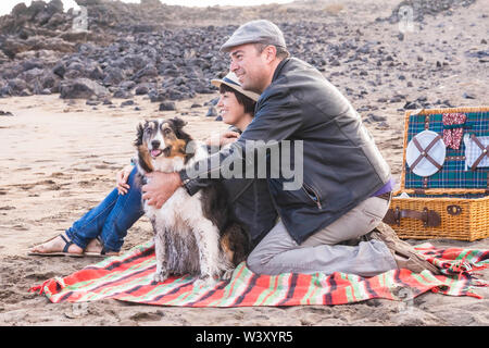 Glücklich nach Familie Menschen bleiben zusammen am Strand mit adorable Funny dirty Dog - Glück und Outdoor Freizeitaktivitäten Aktivität für Mann und Frau in der Liebe Stockfoto