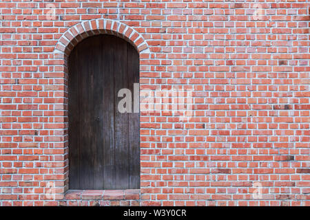 Old Red Brick Wall mit hölzernen Tür. Stockfoto