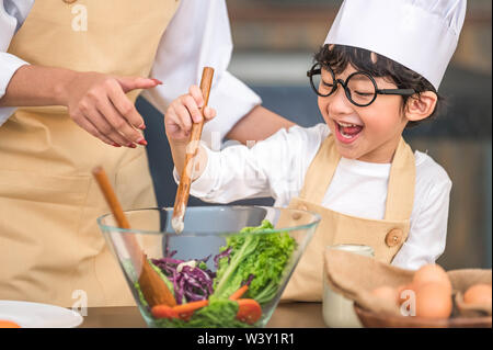 Süße kleine asiatische Happy Boy in Kochen mit Mutter lustig in der Küche zu Hause interessieren. Menschen Lebensstile und Familie. Hausgemachte Speisen und Zutaten conce Stockfoto