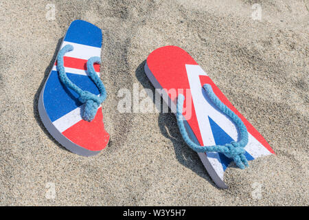Flipflops mit GB-Flagge / Union Jack am Sandstrand - für 2021 Aufenthalte in Großbritannien, Urlaub zu Hause, Aufenthalt in Cornwall, Badeurlaub, Flip-Flop-Schuhe. Stockfoto