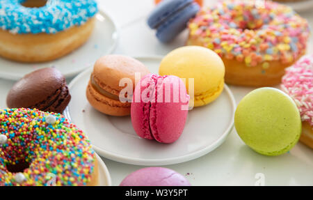 Französische macarons und Donuts auf Holztisch, Ansicht schließen mit Details. Stockfoto