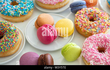 Donuts und Französische macarons auf Holztisch, Ansicht schließen mit Details. Stockfoto