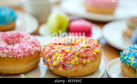 Donuts und Französische macarons auf Holztisch, Ansicht schließen mit Details. Stockfoto