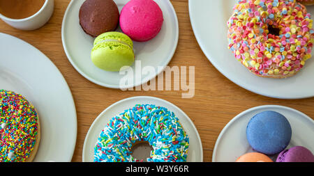 Donuts und Französische macarons auf Holztisch, Ansicht schließen mit Details, Ansicht von oben, Banner Stockfoto