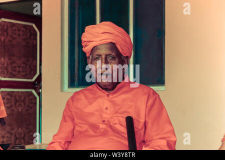Indische Mann in roter Farbe Kleidung - Uttar Pradesh, Indien - 2011 sitzen in der Nähe von Home Stockfoto